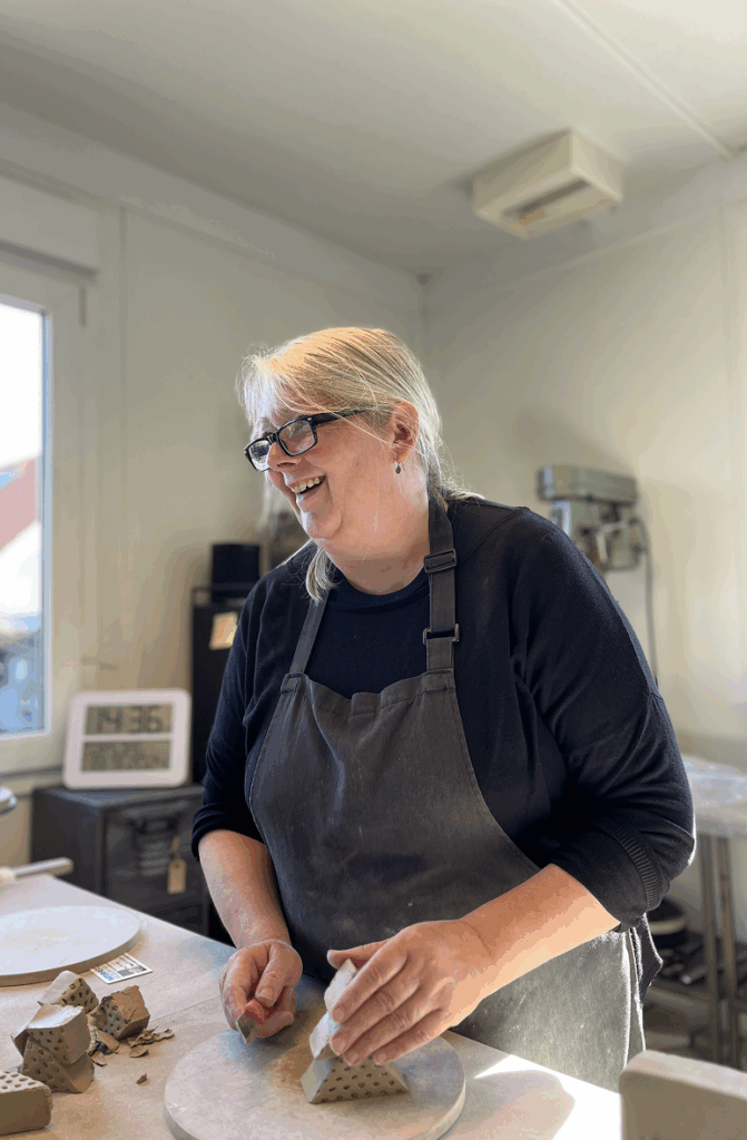 Ejeren Lone Pedersen står og er i gang i sit værksted med at forme ler.