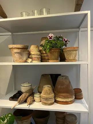 Reol med lerpotter og plantekrukker – brugt på forsiden.