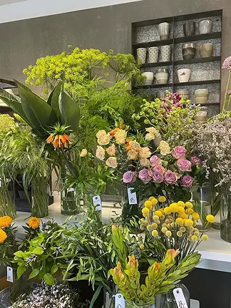 Udstilling med friske blomster foran butiksfacade – billede på vores forsiden.