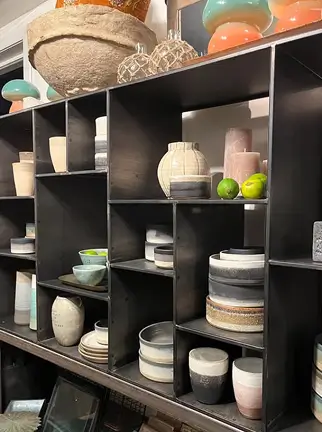 Reol med skåle, krukker og keramik – brugt på forsiden.